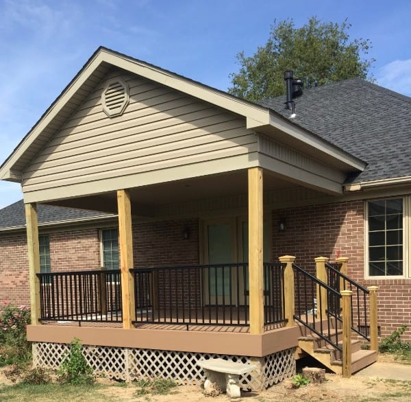 Covered back porch with a shingled gable roof, deck boards, steps, and black railings