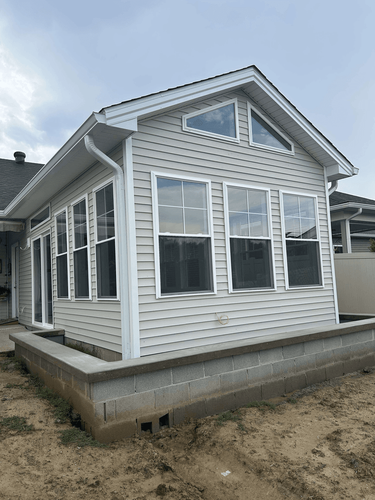 Completed white sunroom addition with a gabled roof and tall windows
