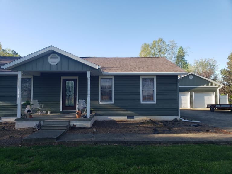 Front view of a renovated home with dark siding, white-trimmed windows, and a new roof