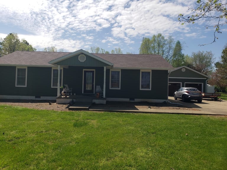 Completed dark-sided home with a new roof, windows, and matching detached garage