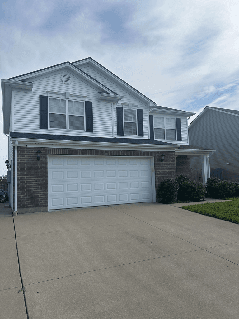 Front view of a completed two-story home with white siding, dark roofing, soffit, gutters, and downspouts