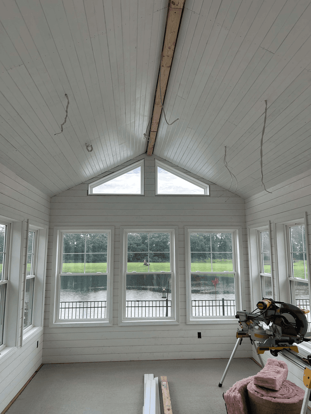 Sunroom interior nearing completion with finished walls, ceiling, and windows