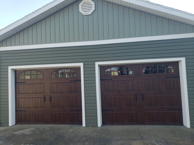 Front view of matching garage doors framed by dark siding and white trim